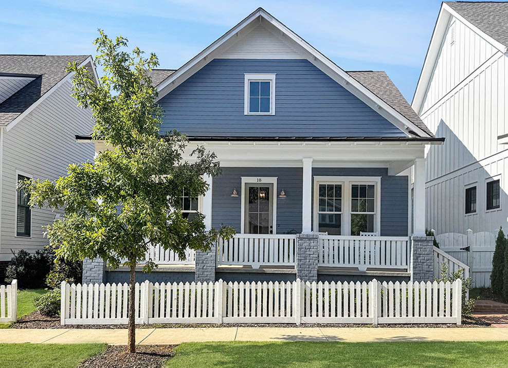 Blue home with white picket fence and cute tree